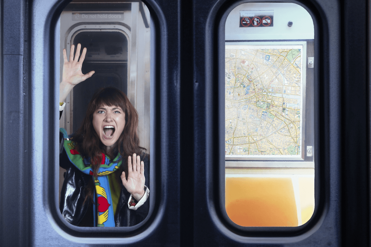 A woman is seen shouting through the window of a train with hands pressed flat against the glass