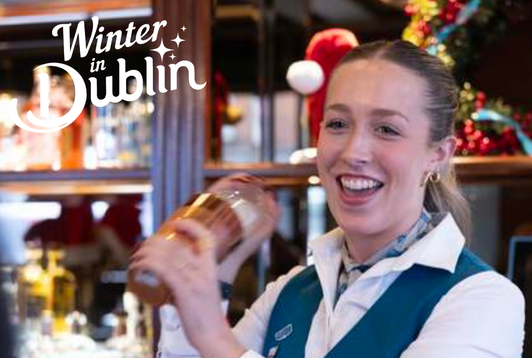 A smiling bartender is shaking a cocktail maker