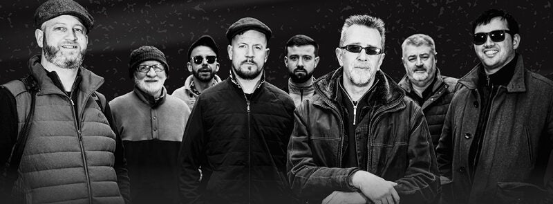 Group of 8 men in outdoor coats, some wearing sunglasses.