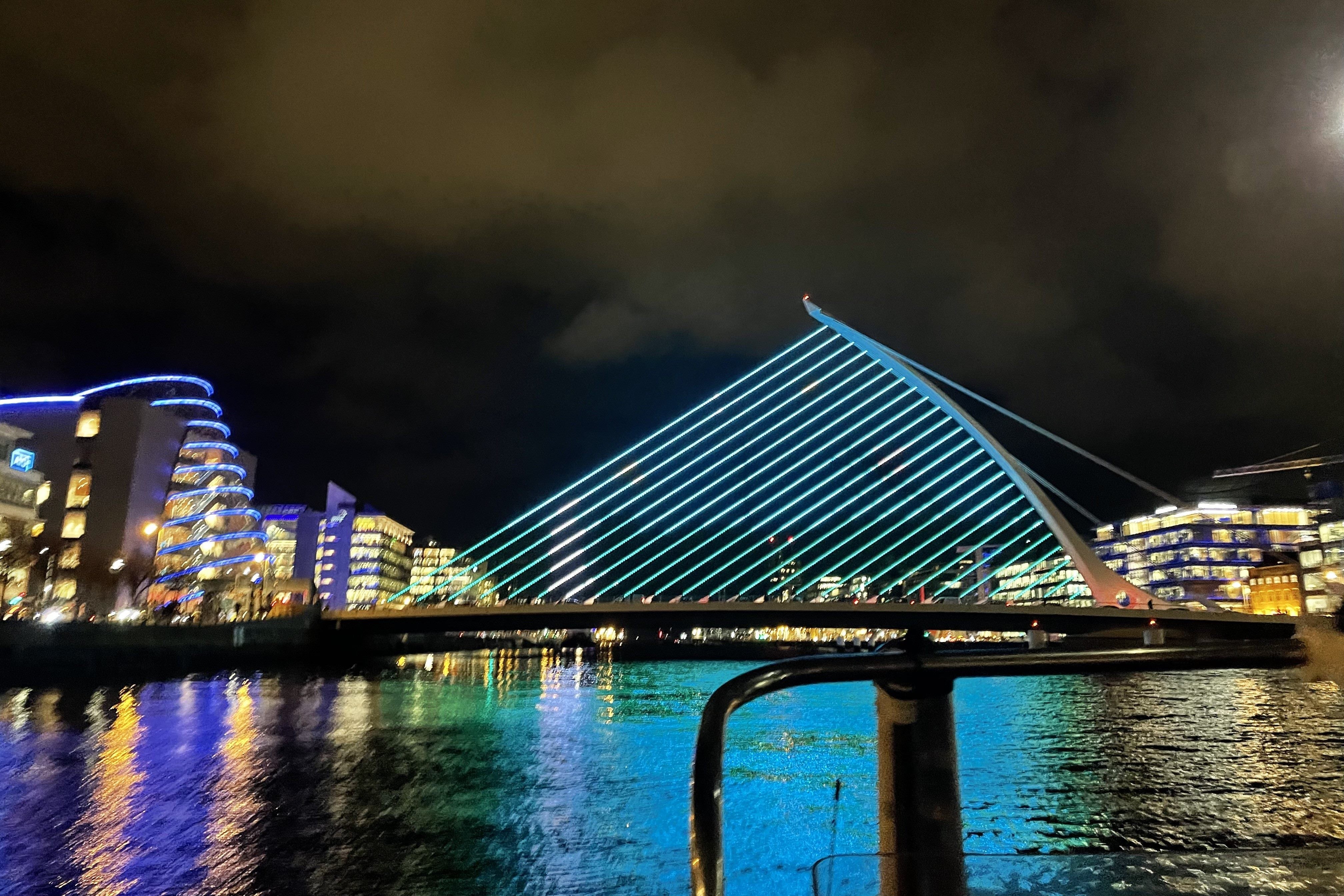 The Samuel Beckett Bridge viewed from one of the boats in the middle of the River Liffey. The bridge is illuminated on blue lights as part of a display.