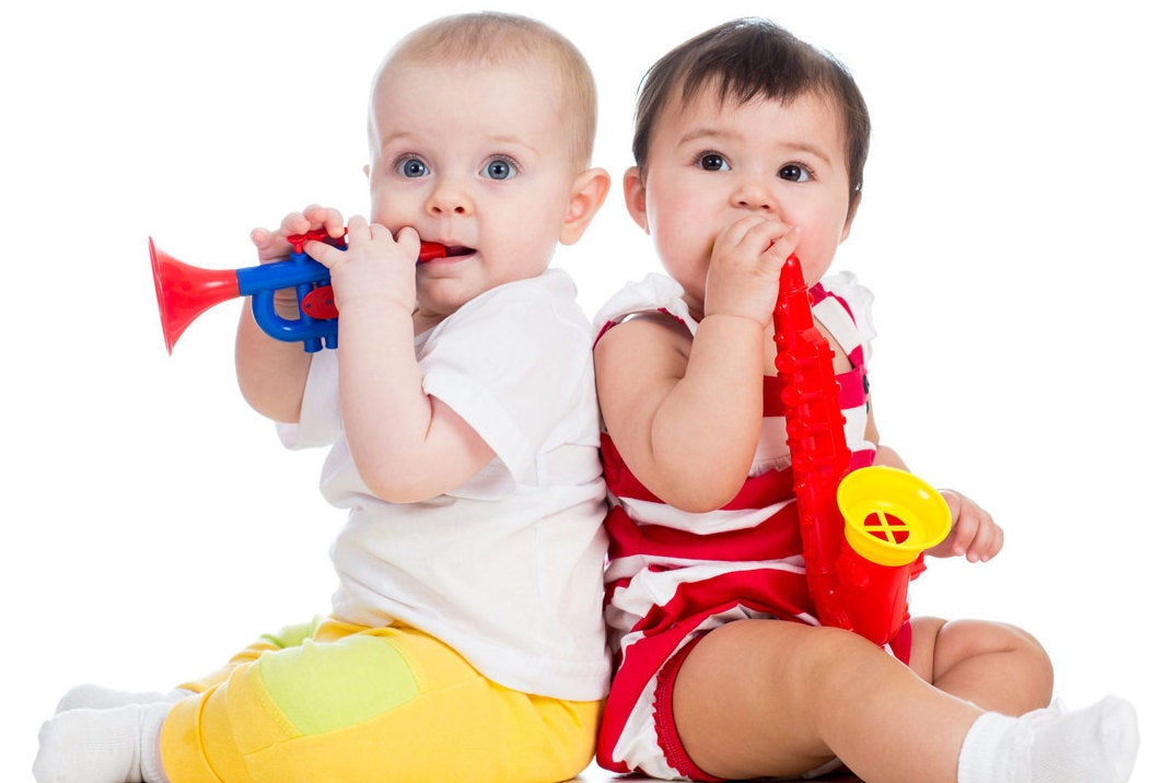 2 babies seated back to back with plastic wind instruments