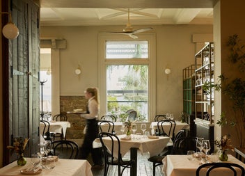 A bright dining space with large window in the background and a server working