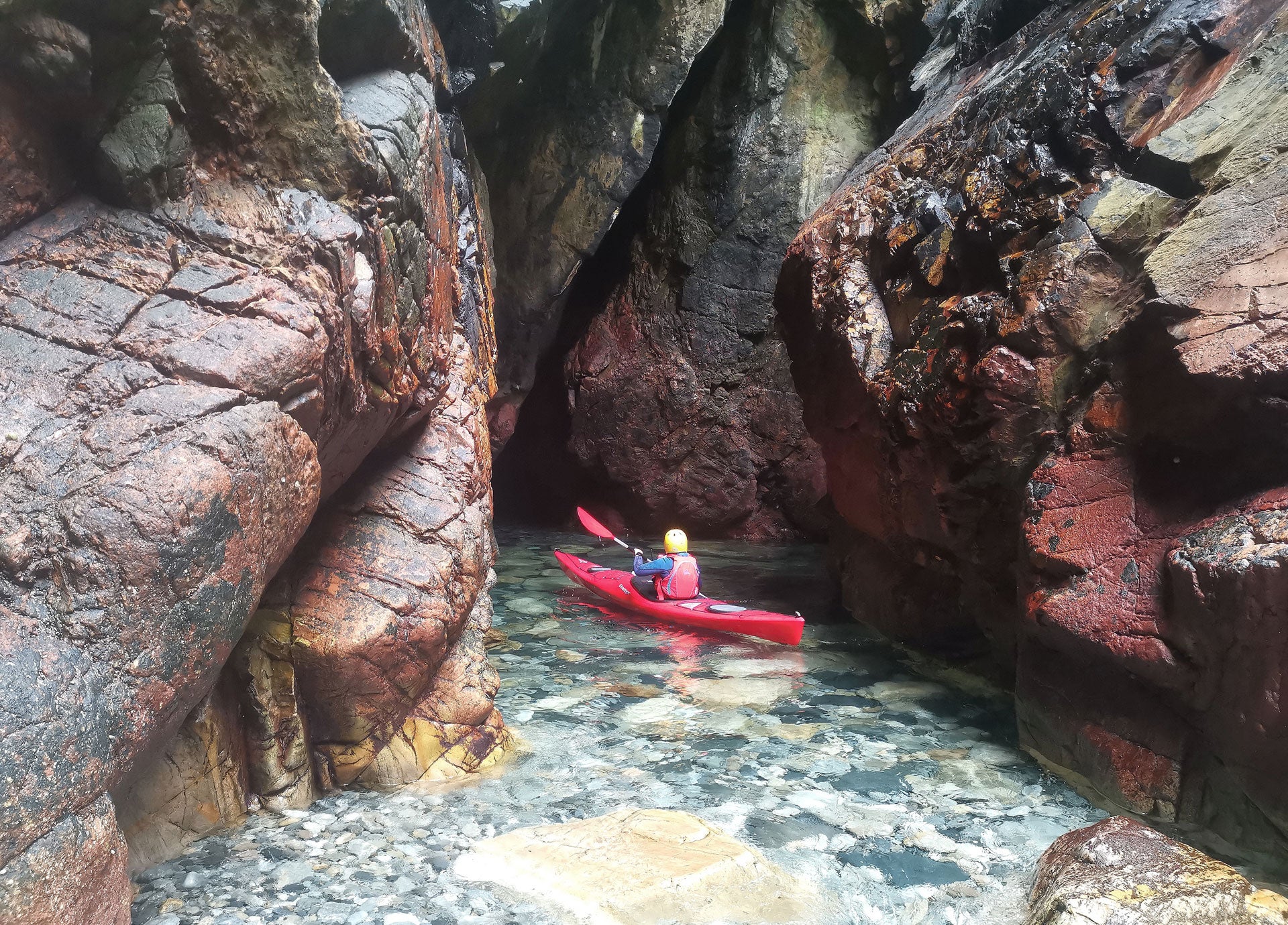 Sea Kayaking Donegal kayaker on the water near a colourful rocky inlet