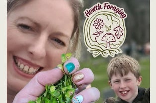 Close up view of smiling woman holding up handful of small green leaves, with young boy smiling in the background.