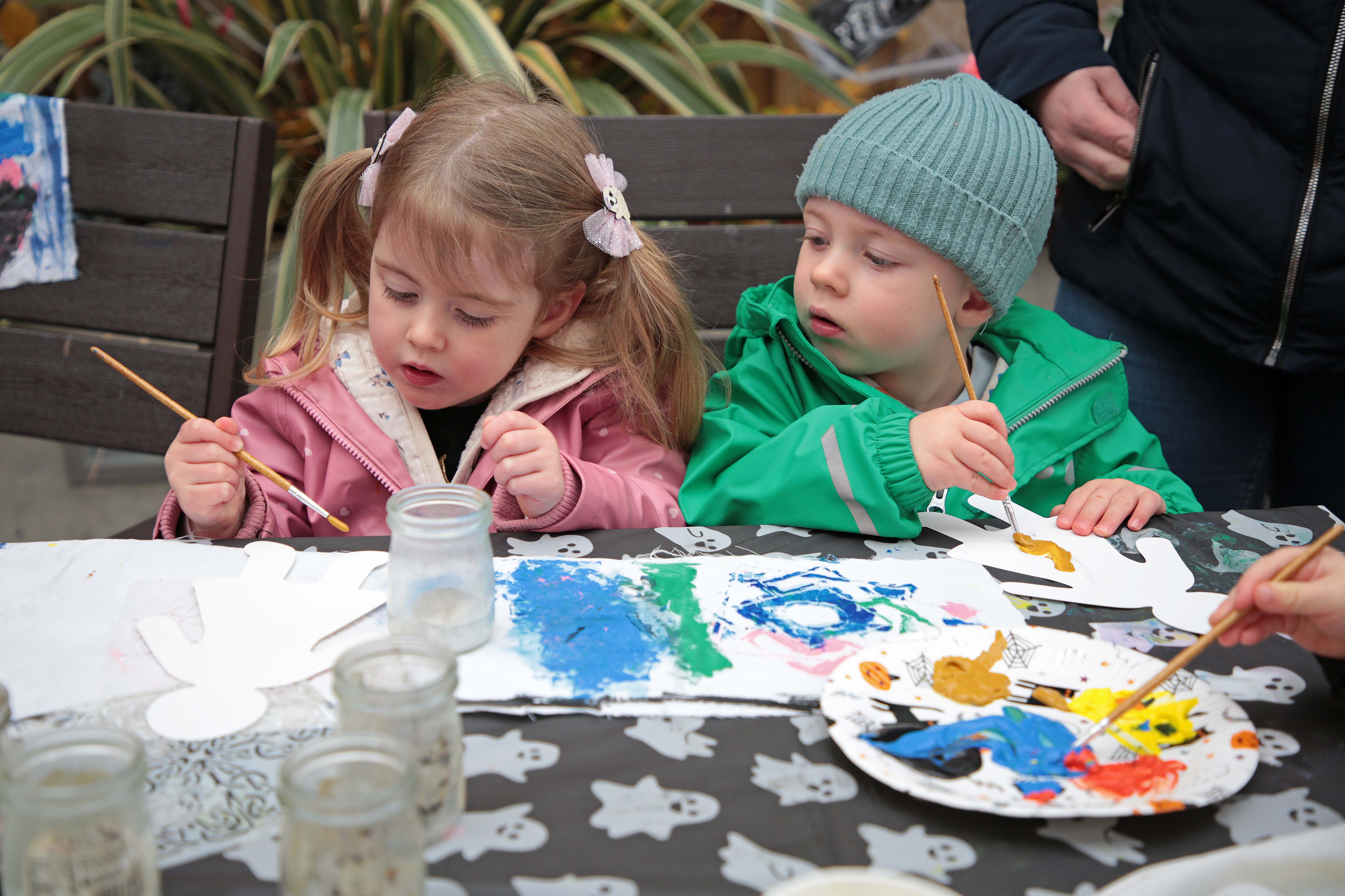 little boy and a little girl sitting together colouring (green and pink jackets)
