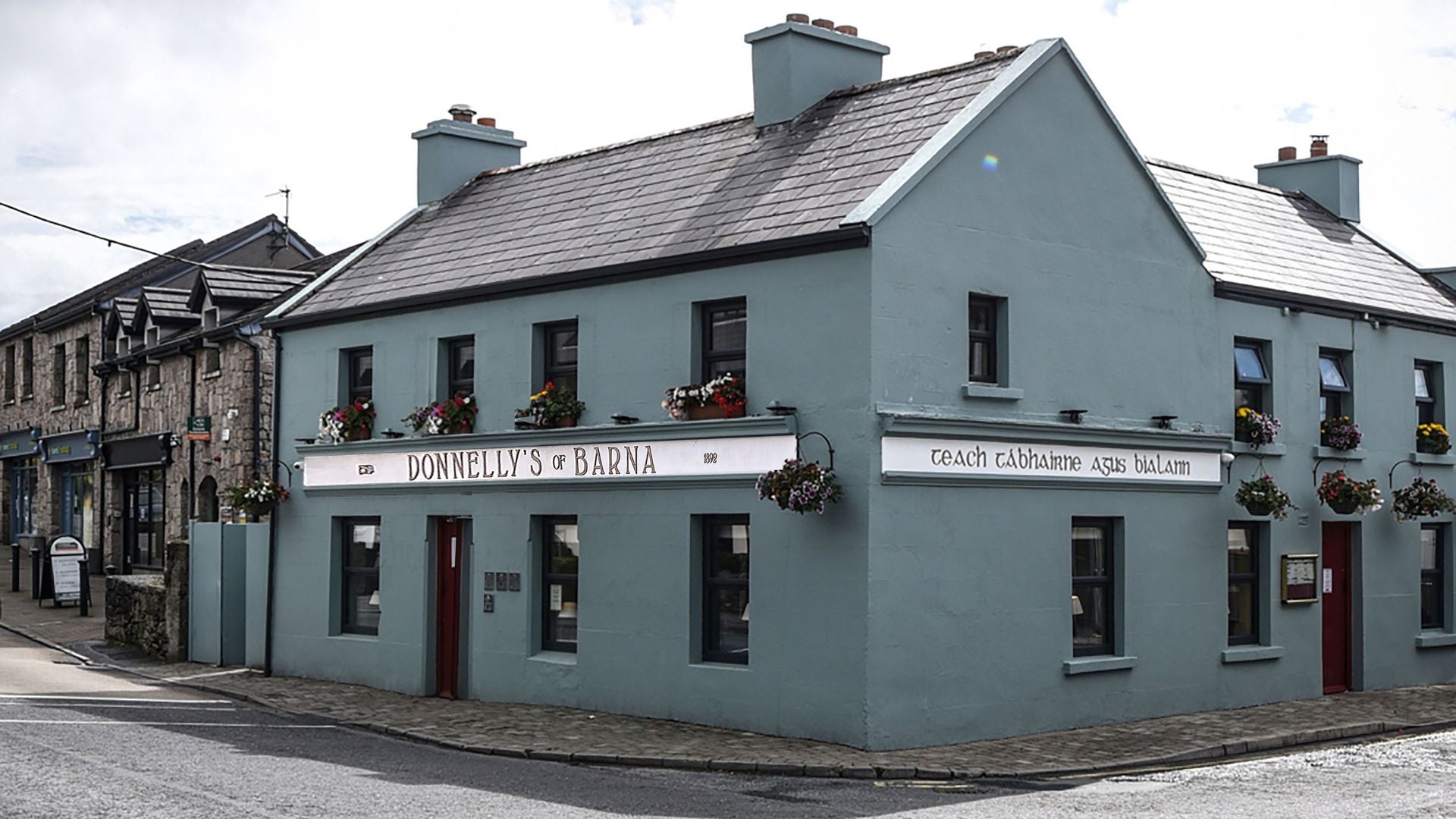 The exterior of a two storey pub and restaurant on a corner painted a mainly grey colour