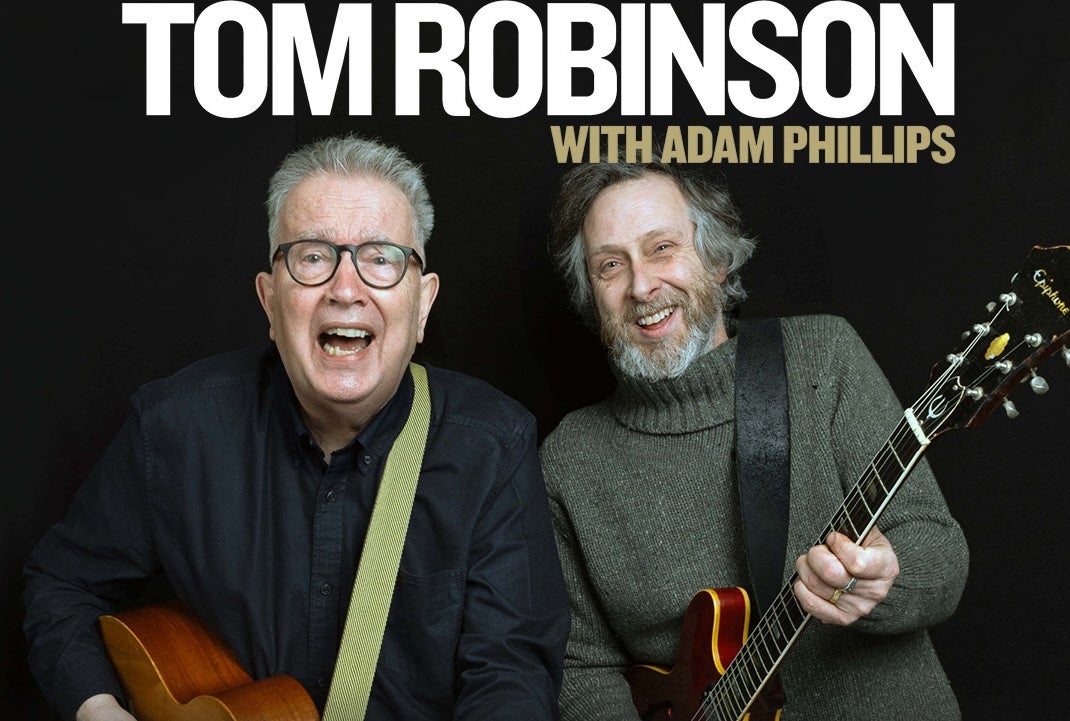 2 laughing older men both strumming guitars.
