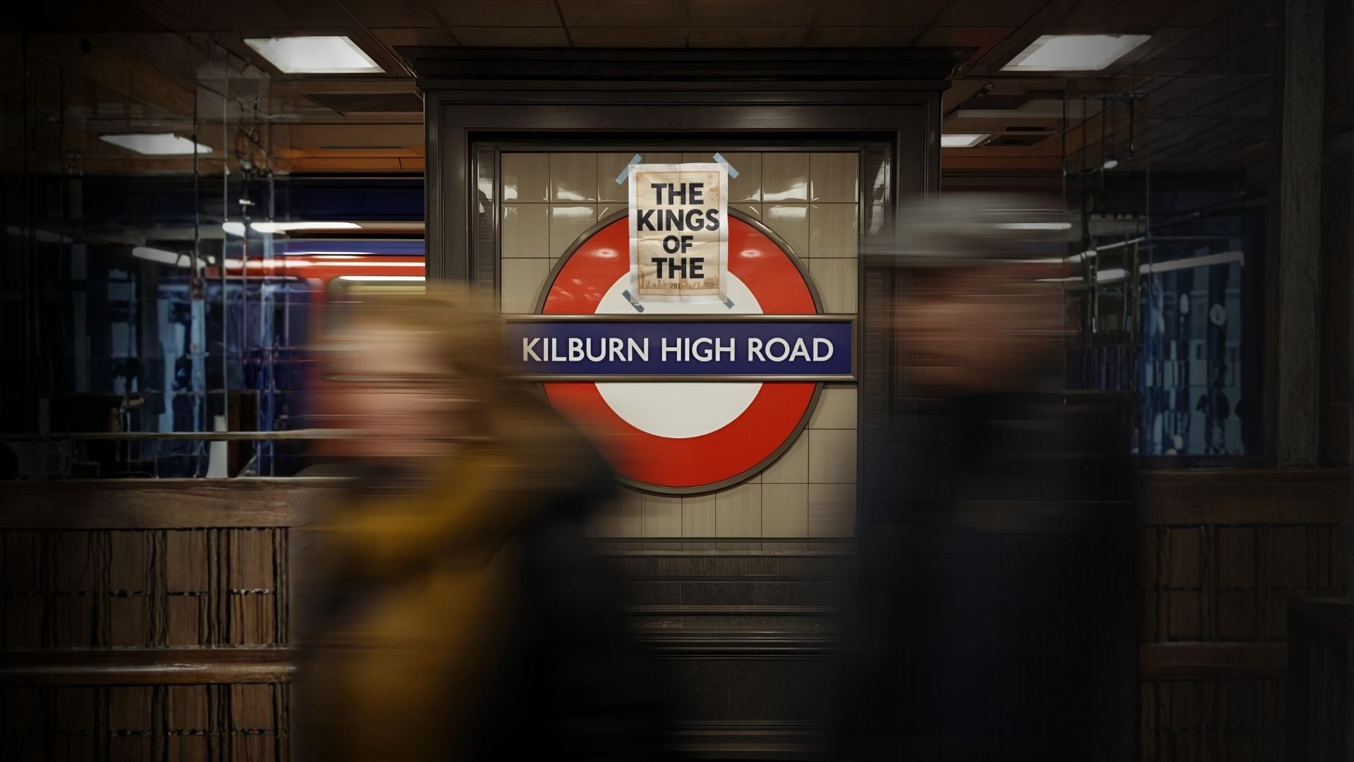 The Kings of the Kilburn High Road, view of a tube station sign with poster tapped to the top of it.