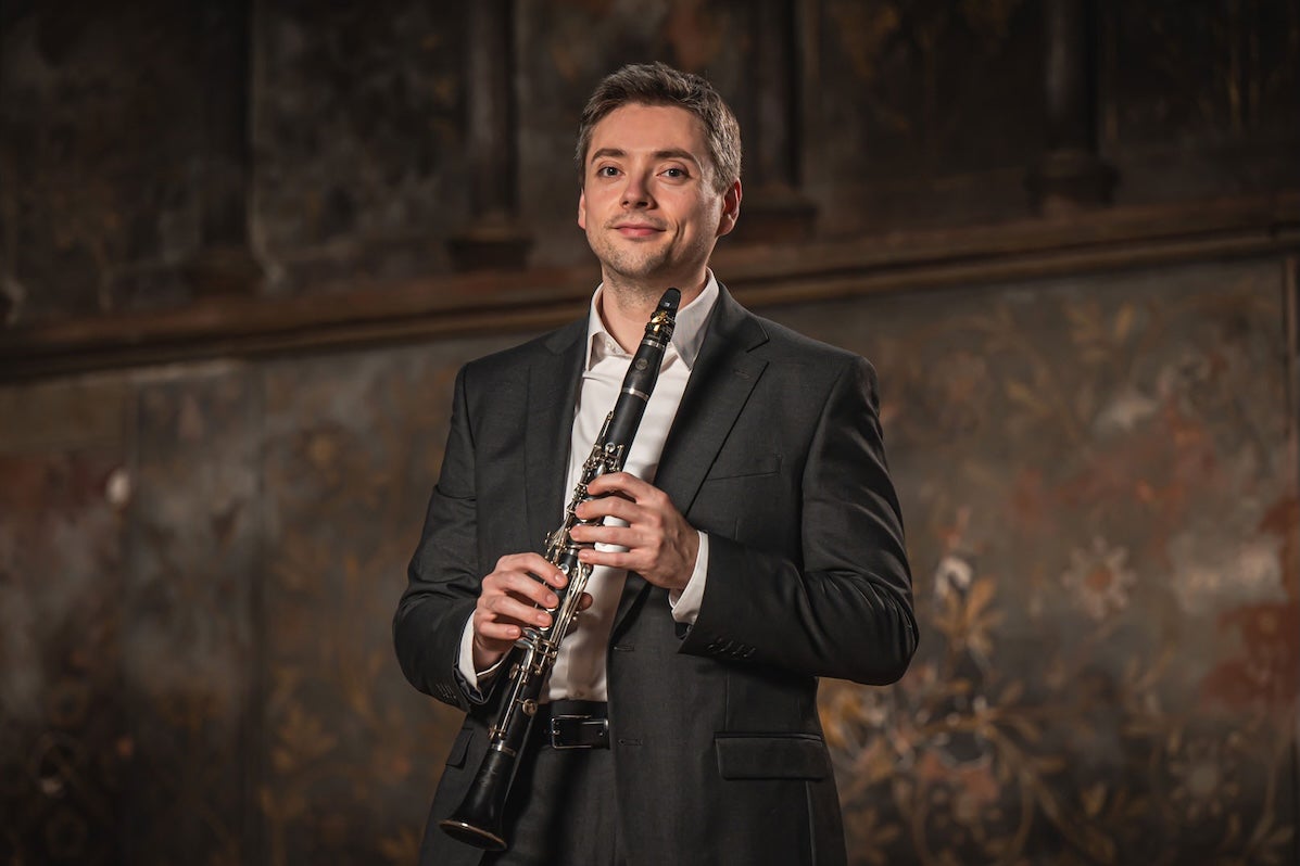 A slightly smiling man holding a clarinet