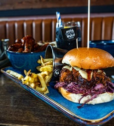 Burger and chips served with wings on the side at Hogs and Heifers