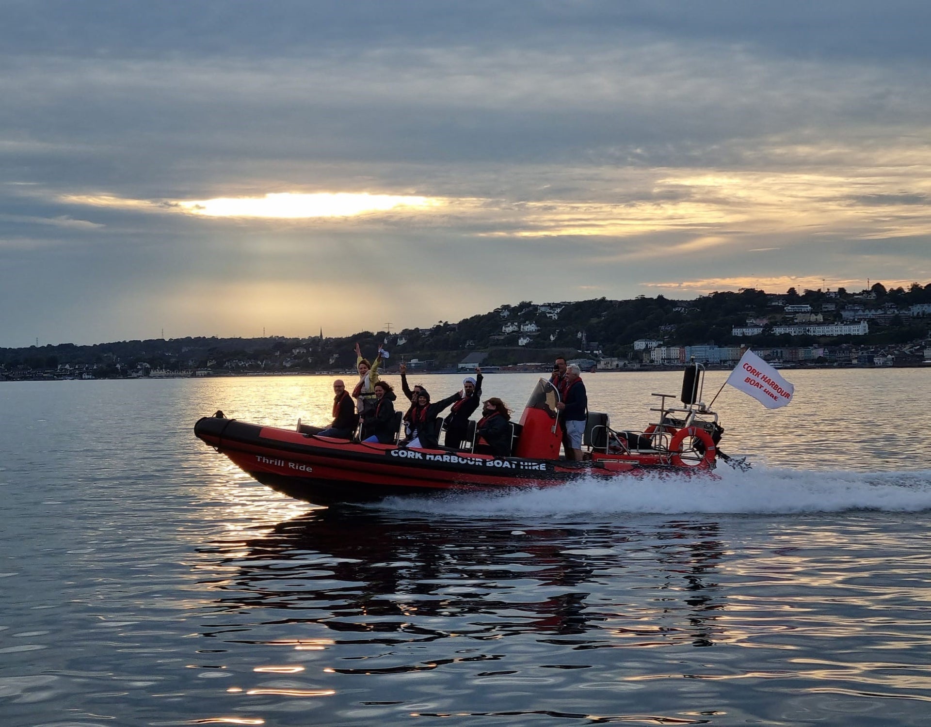 Group on a red and black boat on the water at sunset