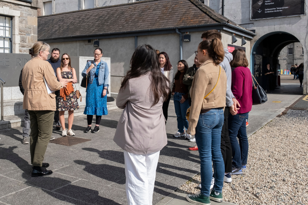 Group of people outside Collins Barracks listening to a tour guide