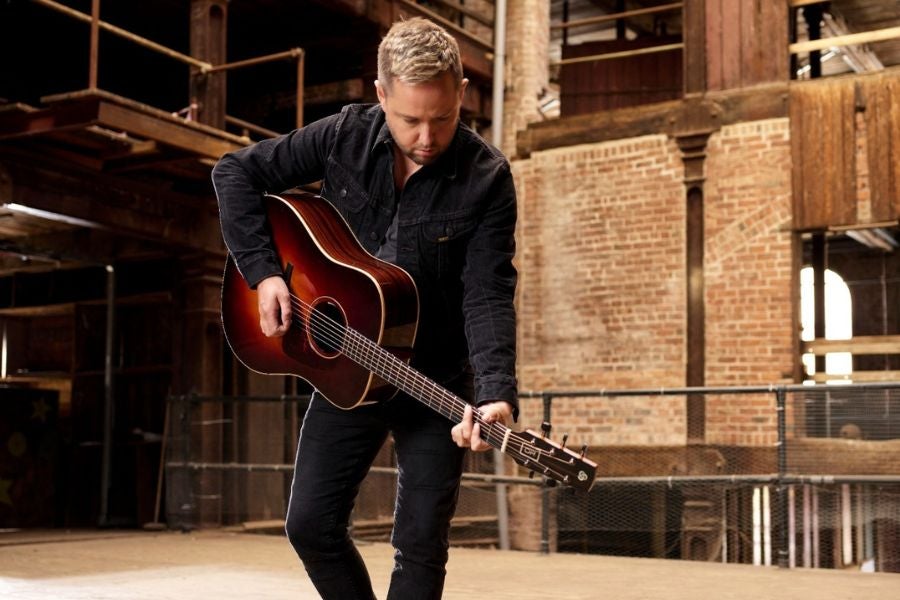 A man playing a guitar looking downwards 