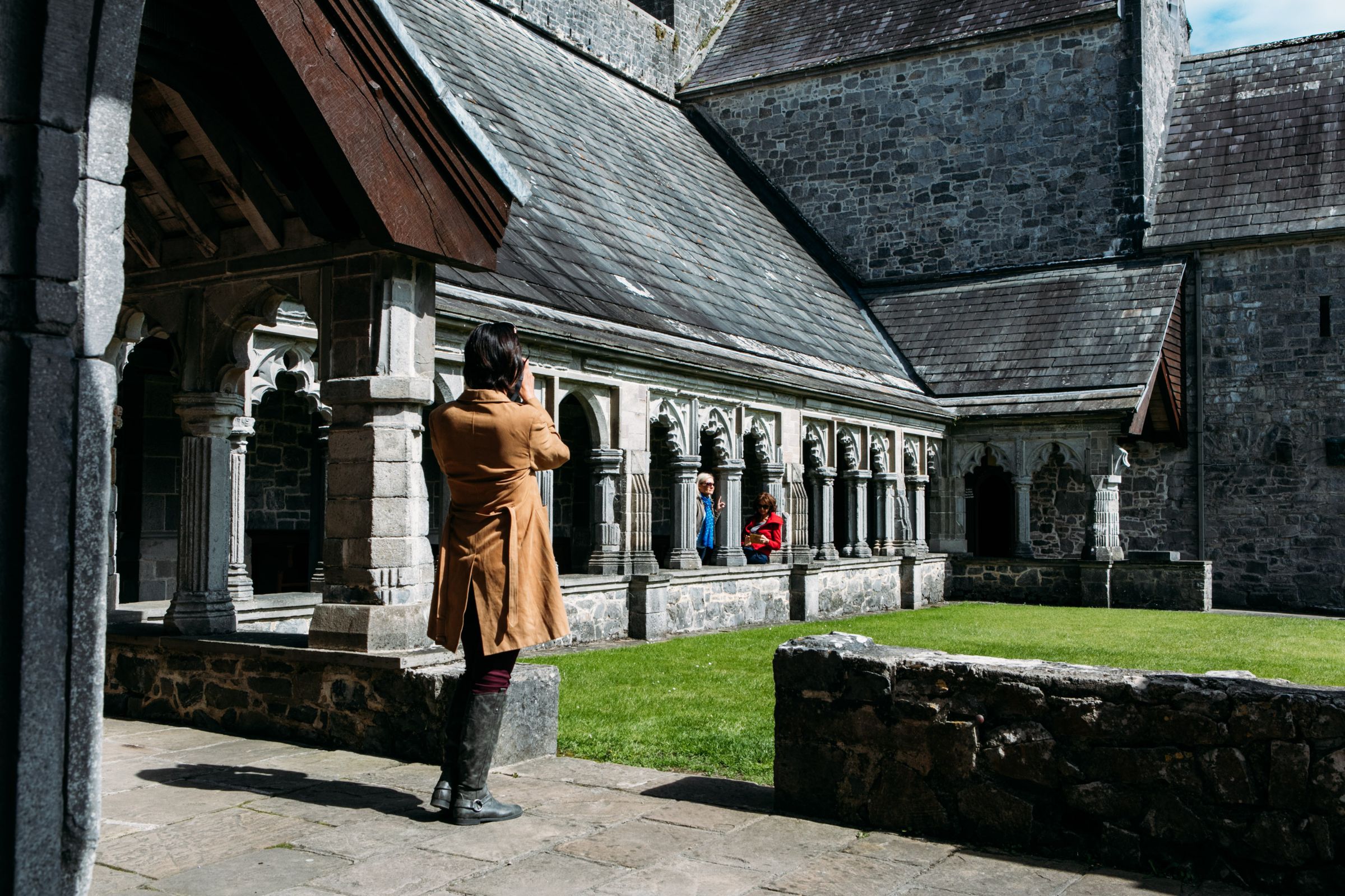 People standing beside grass outside an old stone building