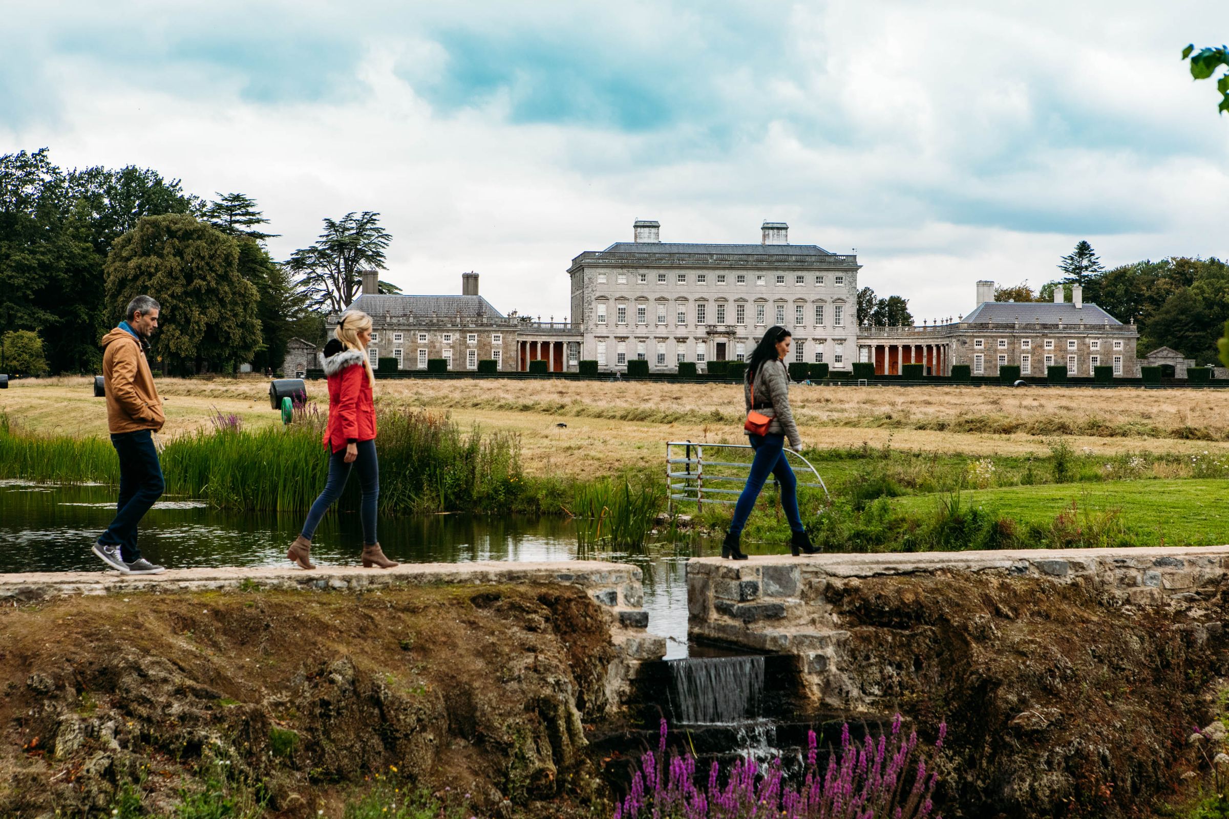 Three people walking on a path in front of Castletown House, Co Kildare