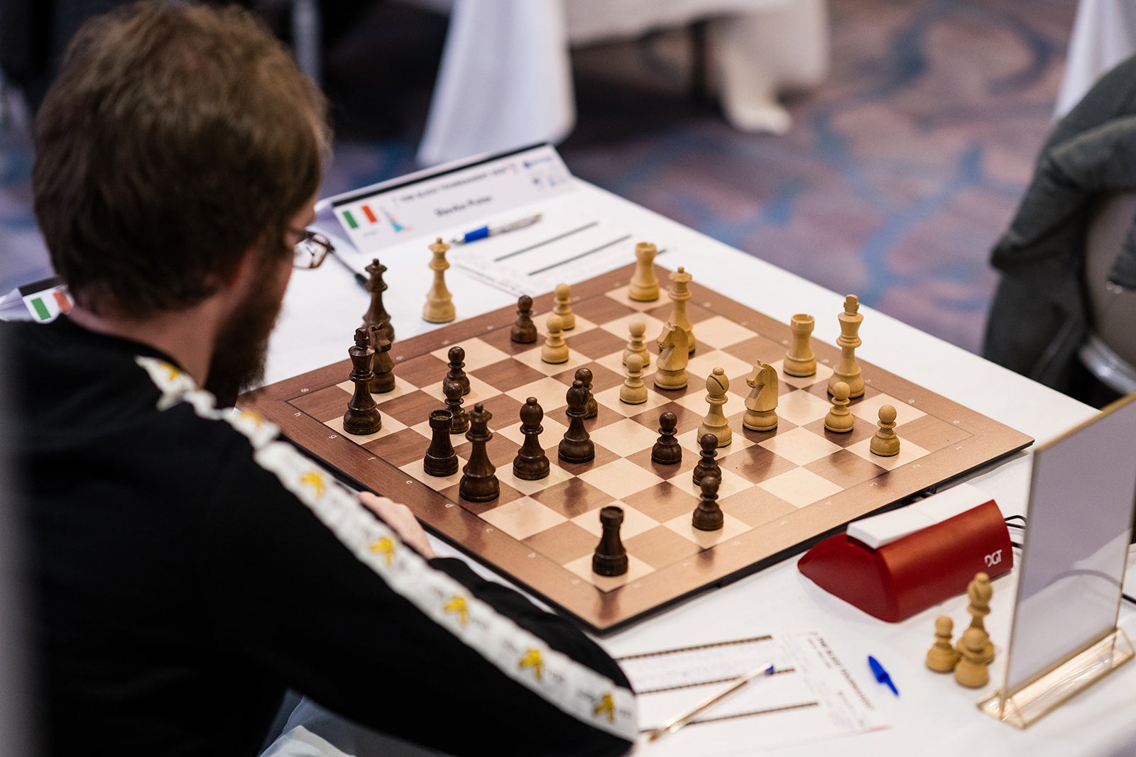 Chess player at board analysing position as black
