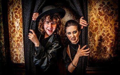 Two scary characters peer out from behind a curtain