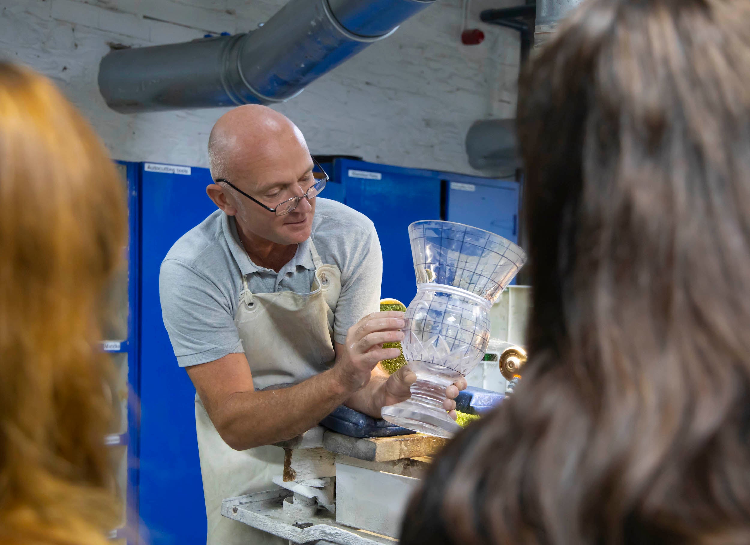 A craftsman in the House of Waterford Crystal in Waterford showcasing a piece of crystal to people.