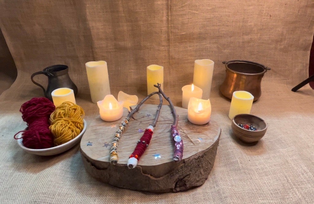 decorative wands sit on a wooden wedge with a hessian backdrop surrounded by candles
