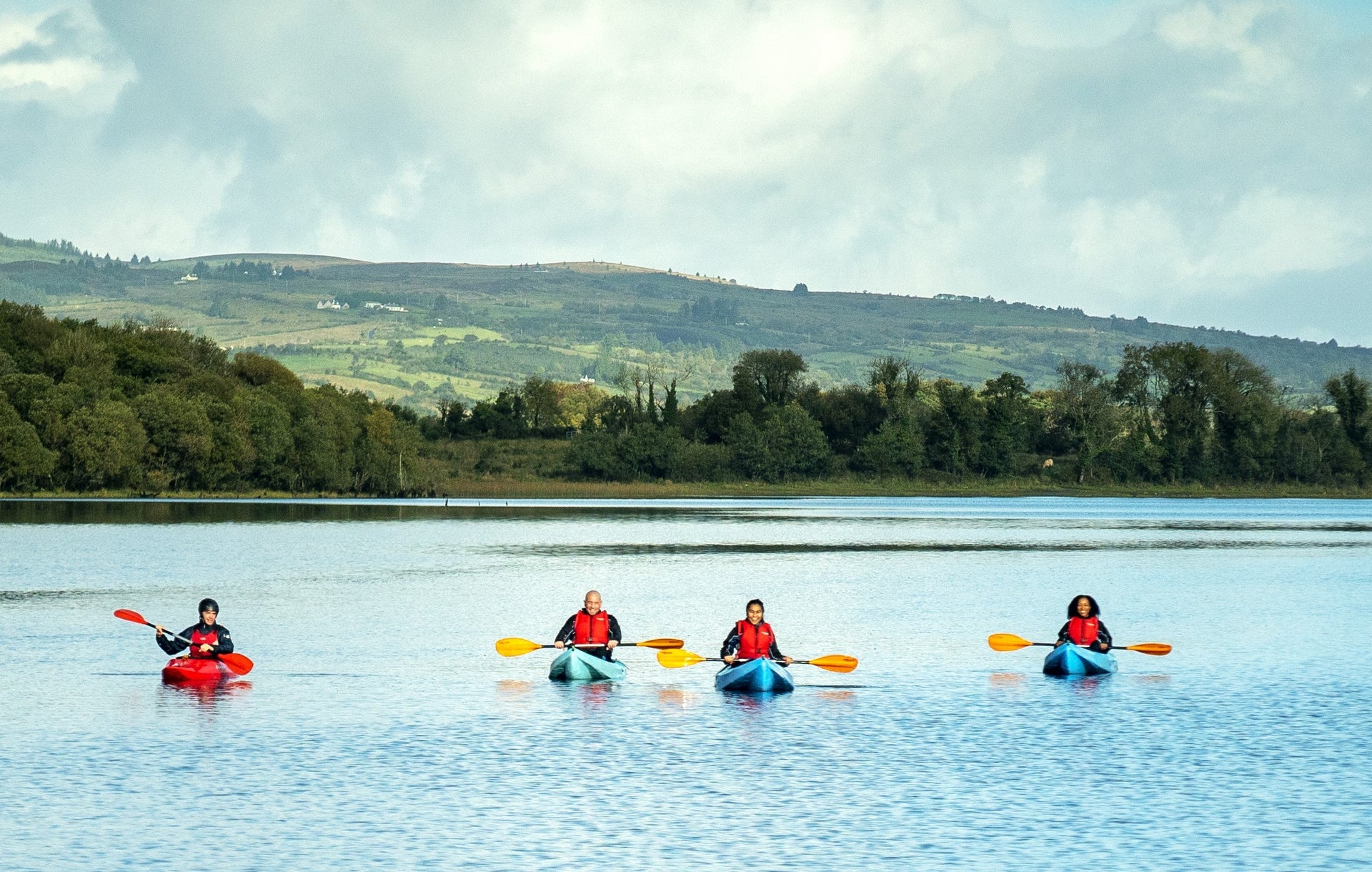 A group out kayaking in the water with the beautiful green landscape in the background
