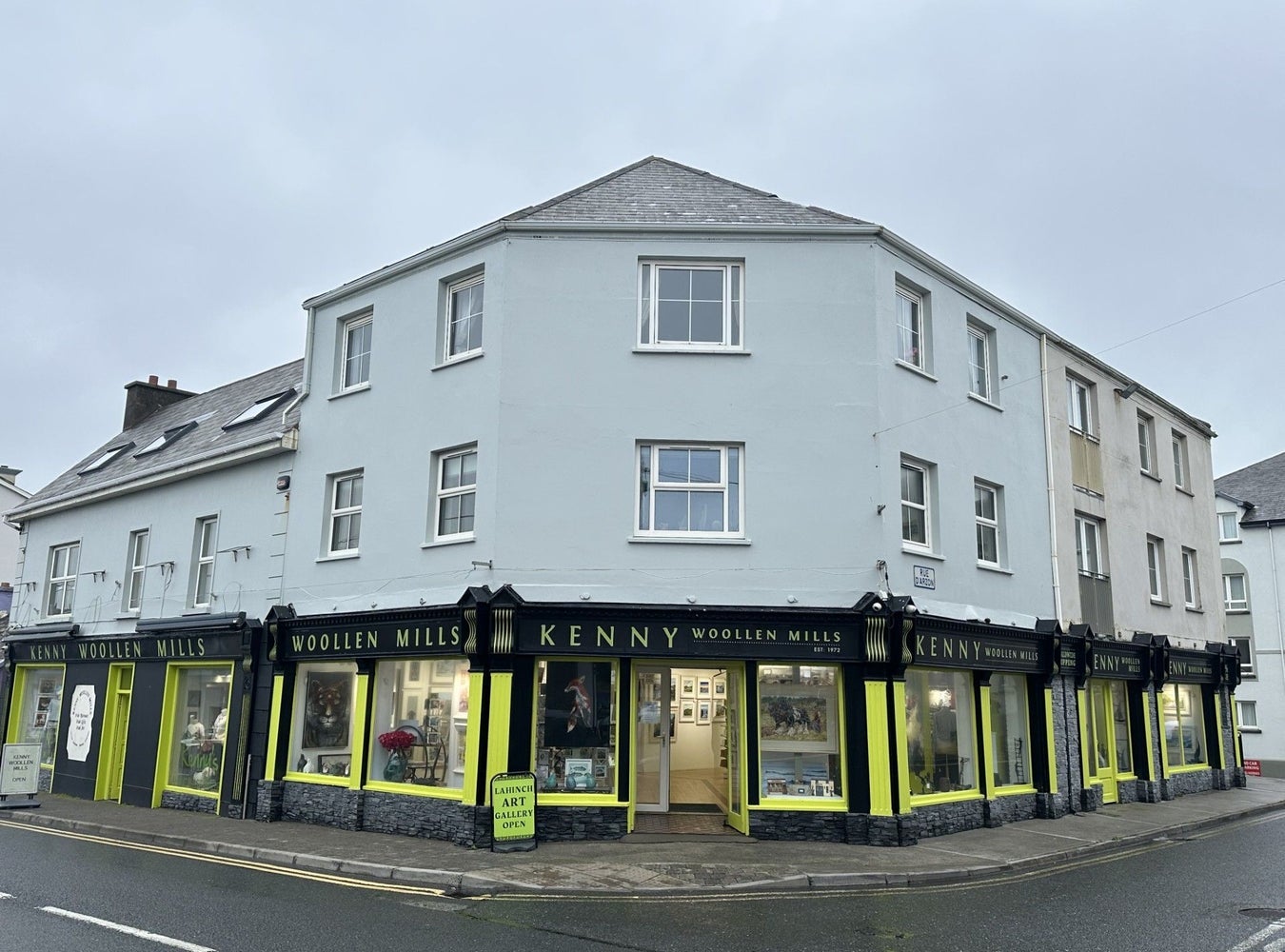 A two storey building on a street with a business name along the top of the door and windows