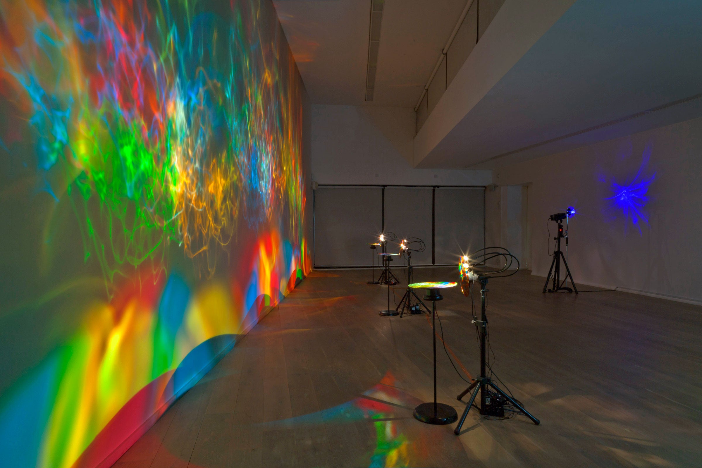 Colourful light show projected on a wall in a gallery