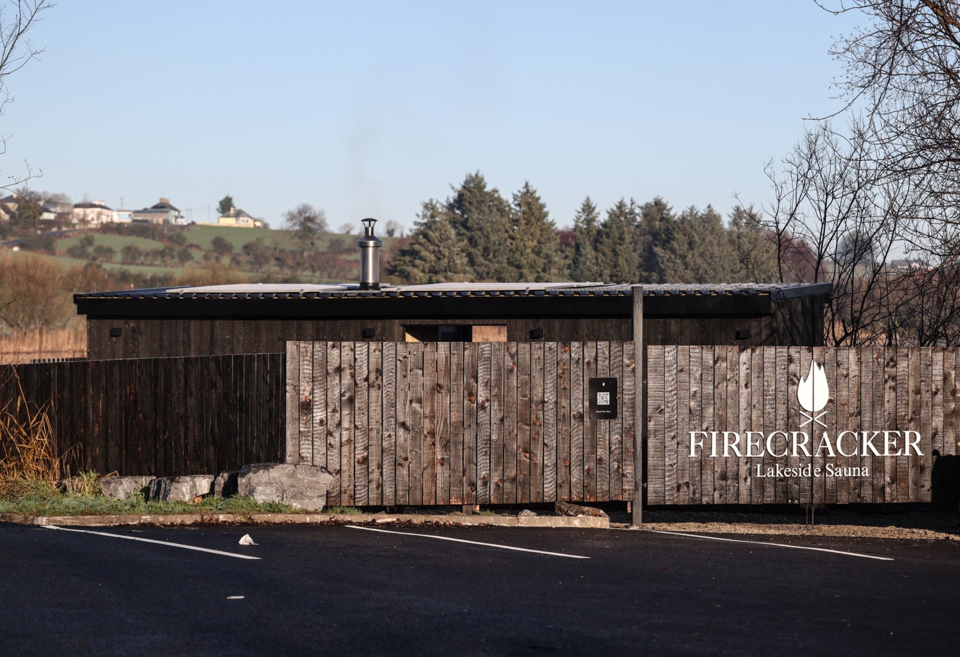 Wooden fencing around an outdoor sauna with trees in the background