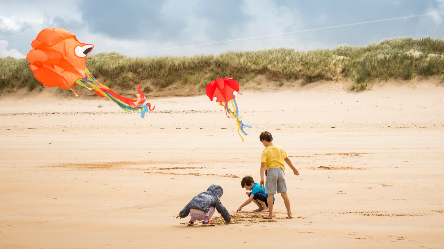 Three children flying colourful kites on Marble Hill Beach