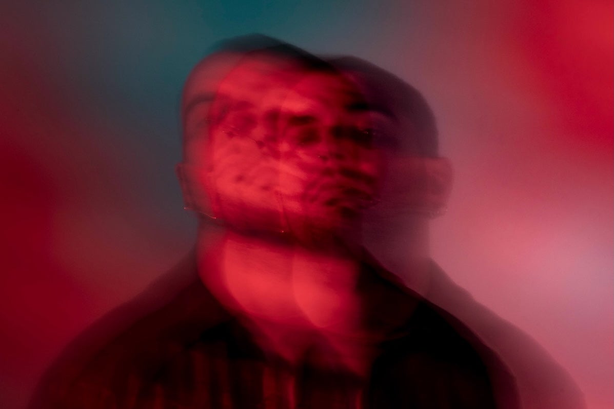 A very blurry headshot of a man in shades of red and black