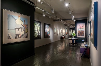 Interior of an art gallery with pictures on walls and subdued lighting