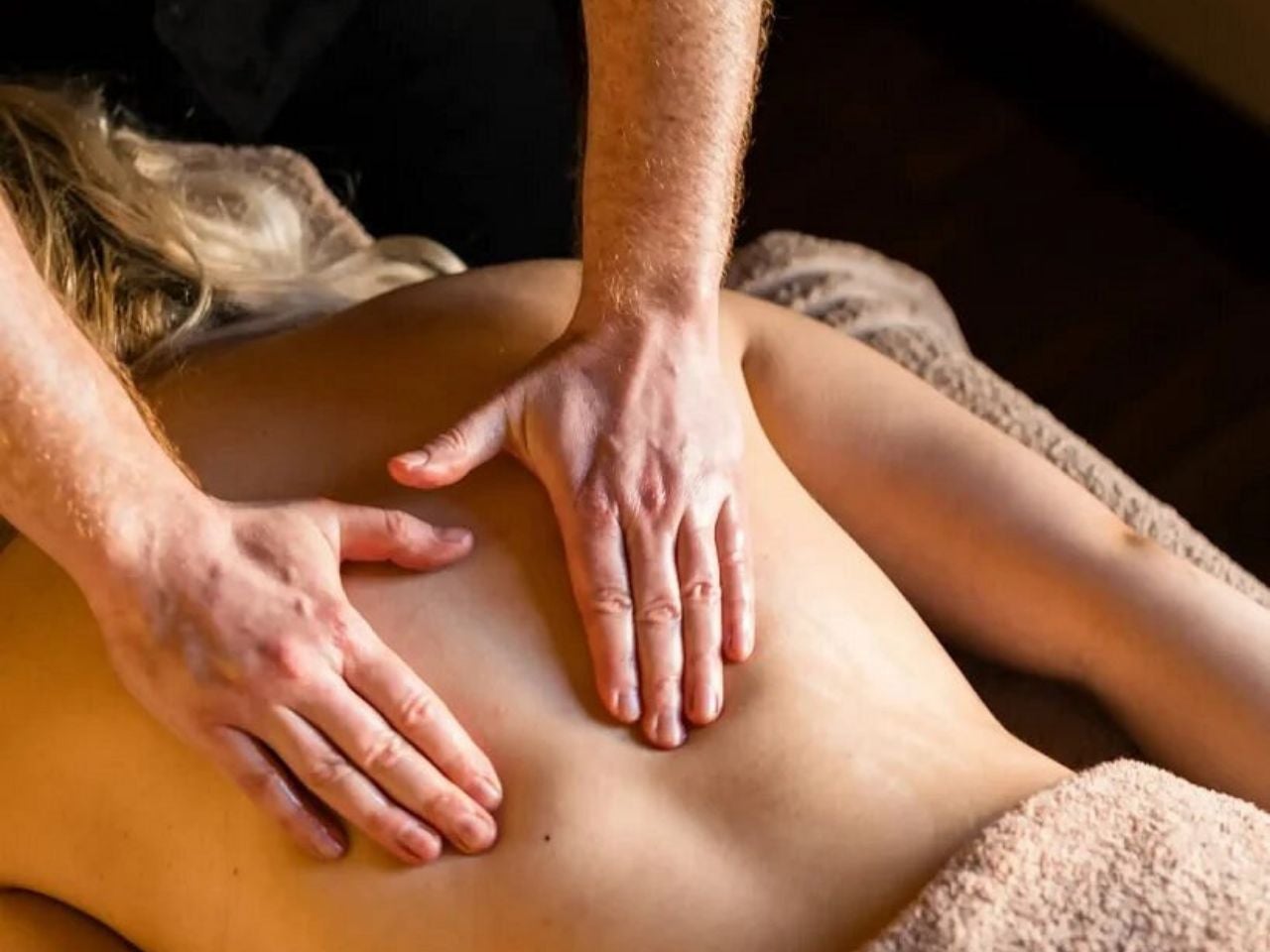 Massage therapist performing a back massage in a calm and relaxing therapy setting