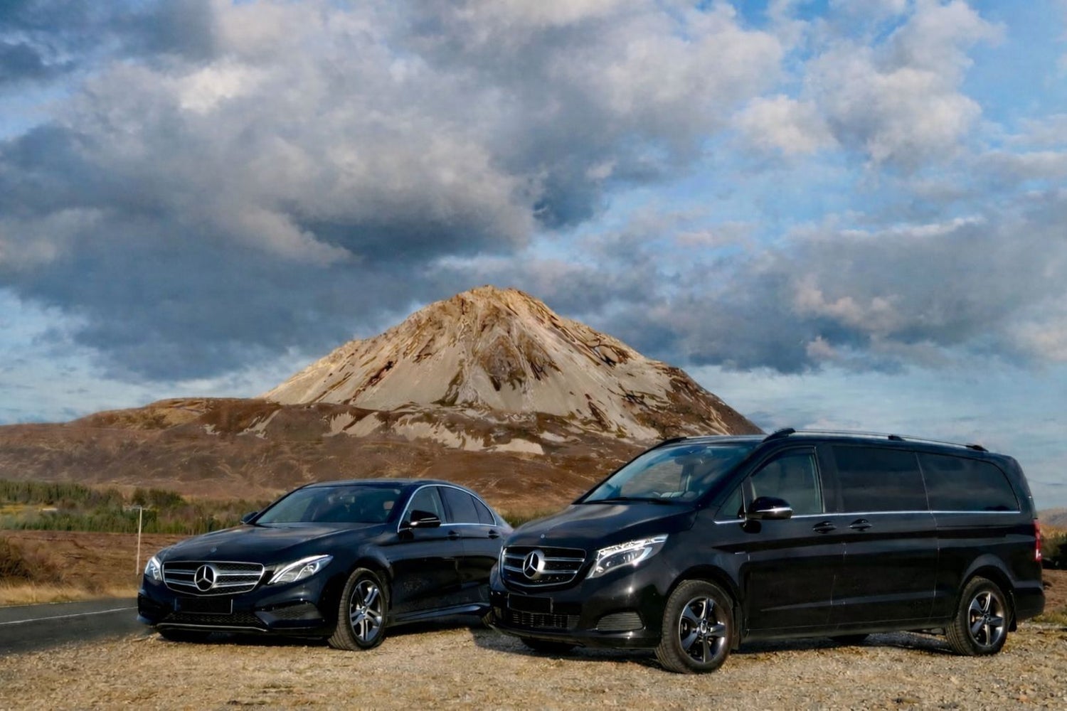 Two black Mercedes vehicles parked in front of a mountain