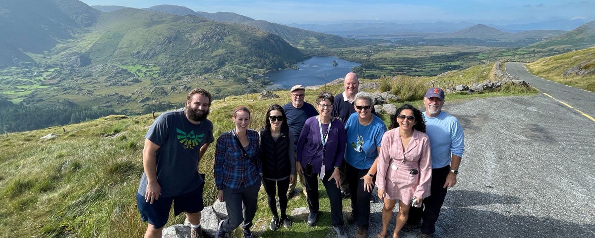 A group of smiling people with hills and the sea in the background