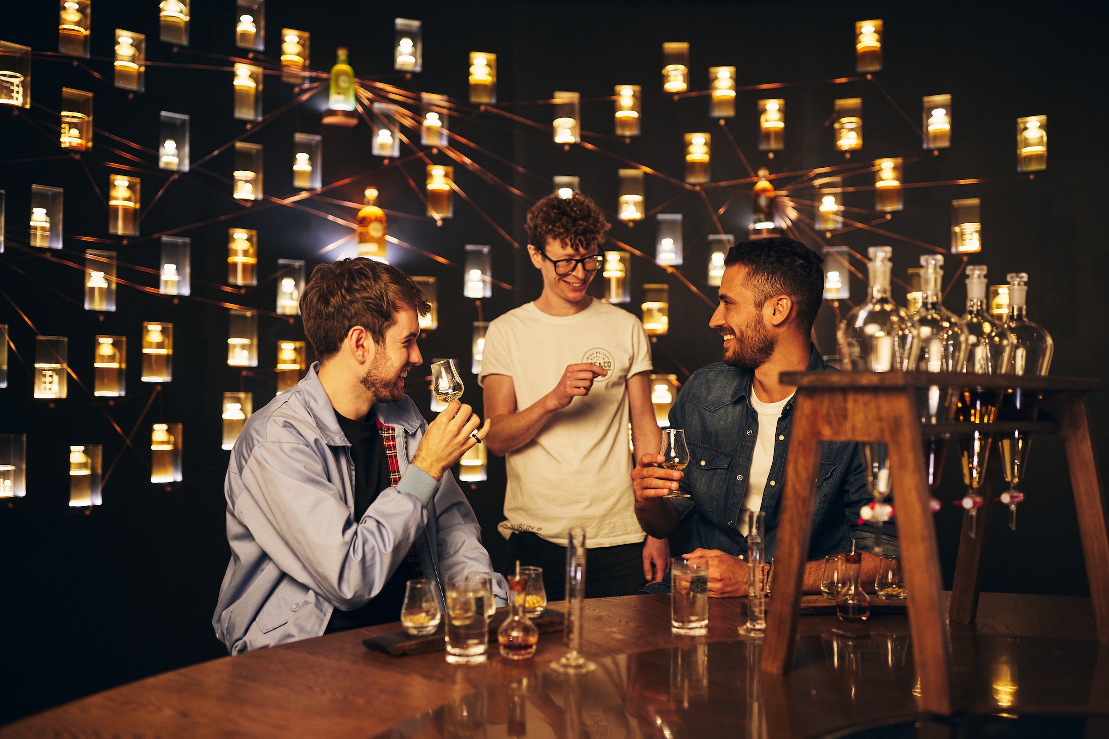Three men enjoy a glass of whiskey inside  Roe & Co Whiskey.