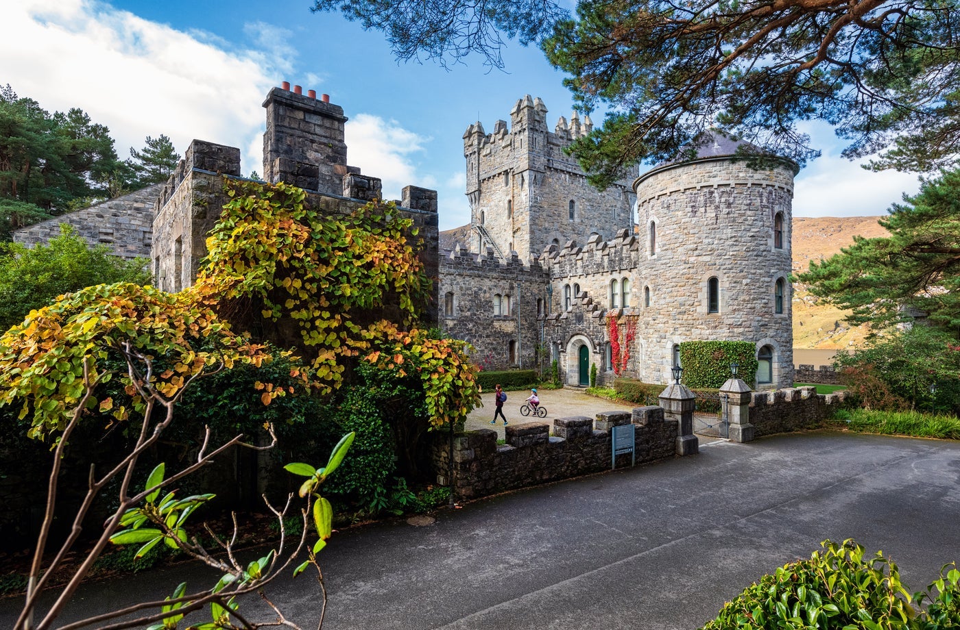 A castle and round tower surrounded by green shrubbery