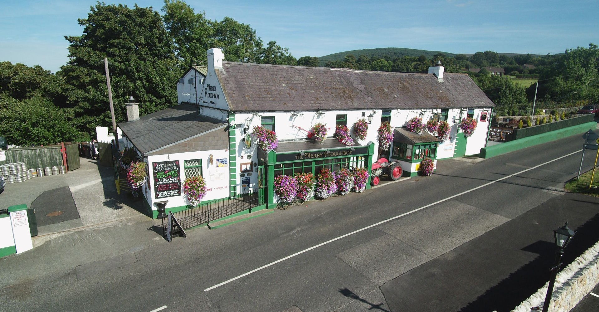 The exterior of the Merry Ploughboy Pub which is a white building with green trim and shopfront.