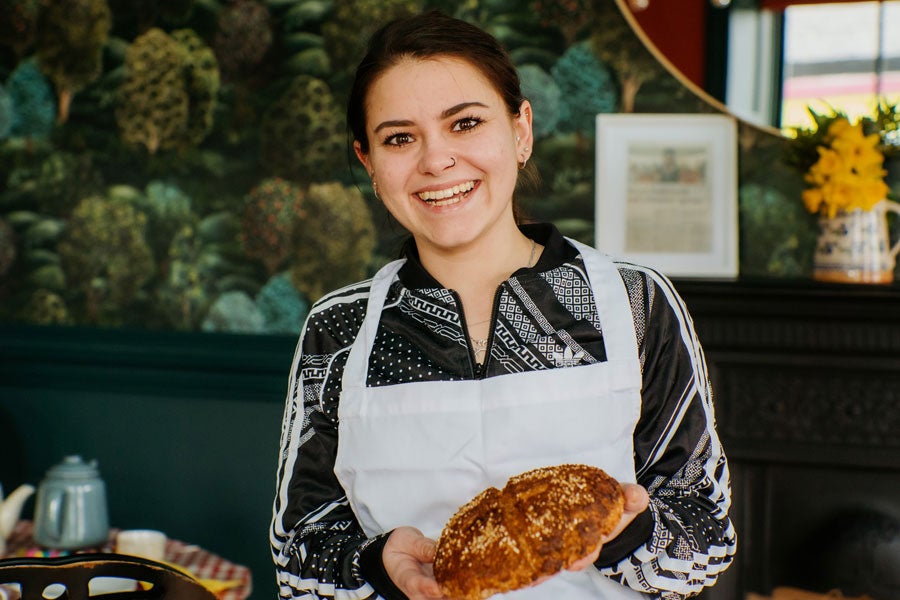 A lady in an apron holding an Irish soda bread scone