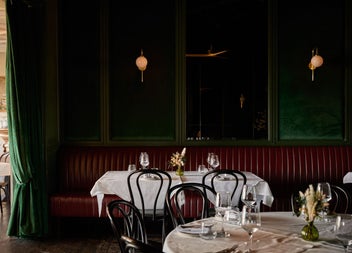 Tables set for dinner in a restaurant with dark green background