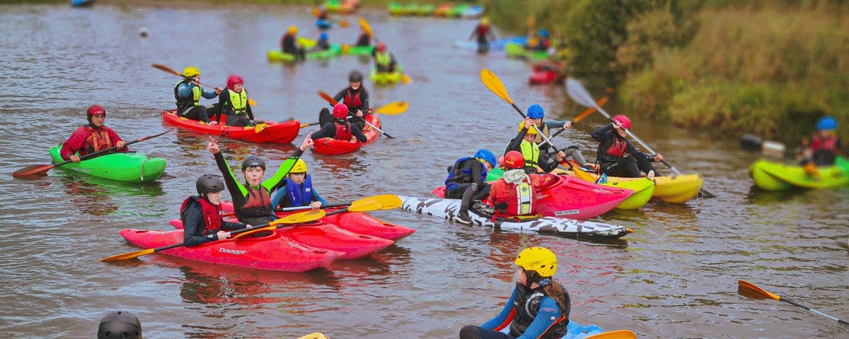 Several kids in kayaks on a river