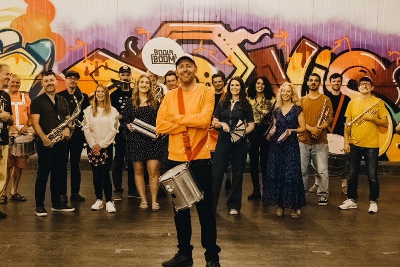 A large group of smiling people, most holding musical instruments.