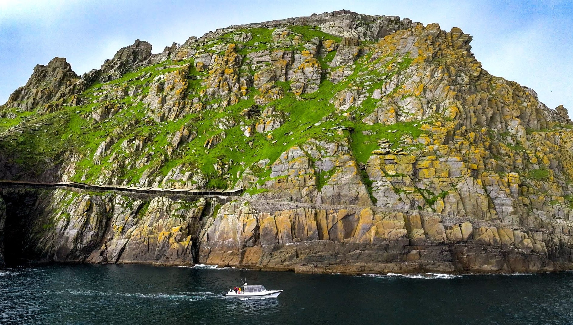 View of Skellig Michael from the sea with a tour boat sailing past
