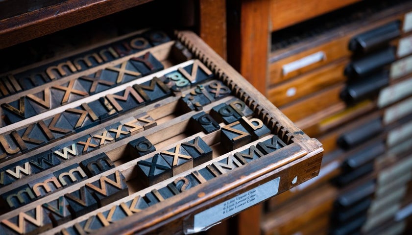 A case of wooden type partially pulled out of a type cabinet.