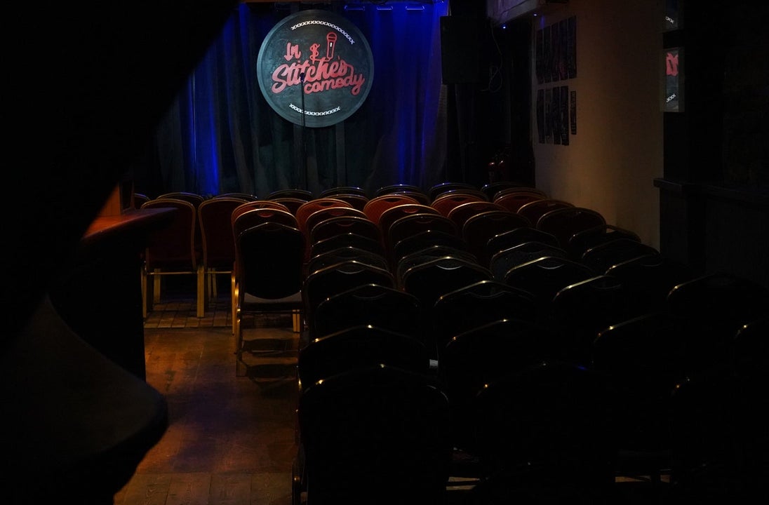 A dimly lit stage with a comedy club logo