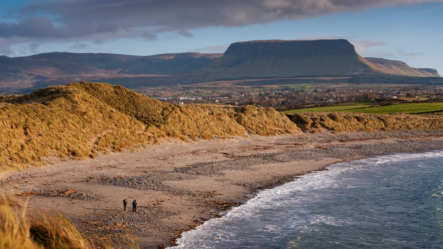 Two people walking Streedagh Beach, Co Sligo with Benbulben in th background.