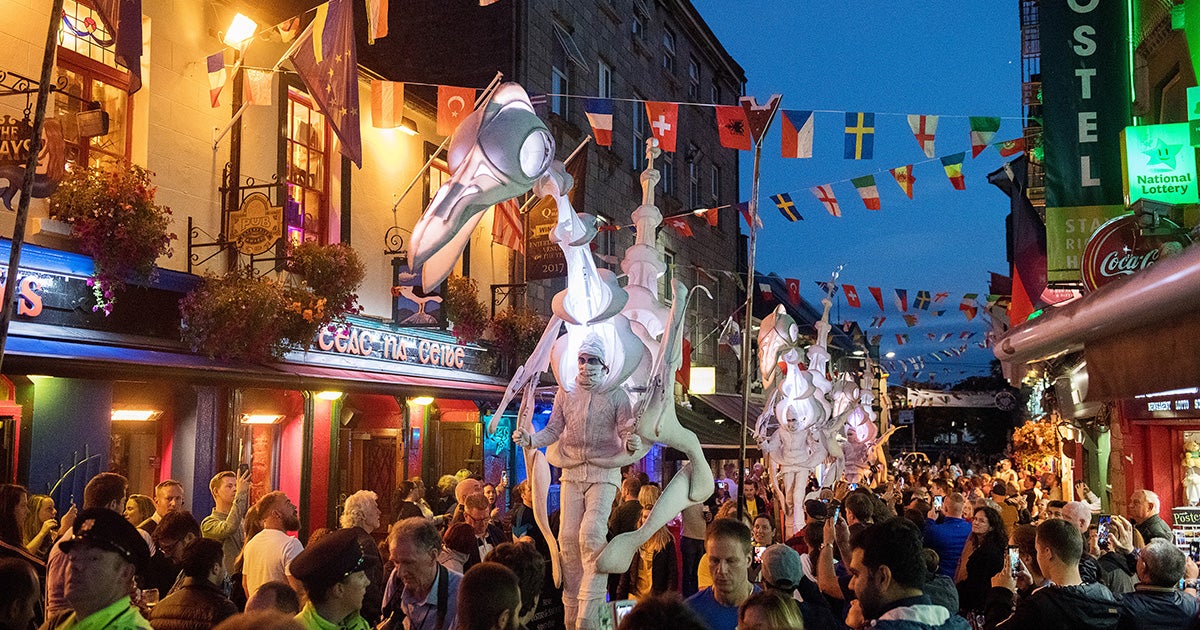 Crowds of people watching a street parade during during the Galway International Arts Festival