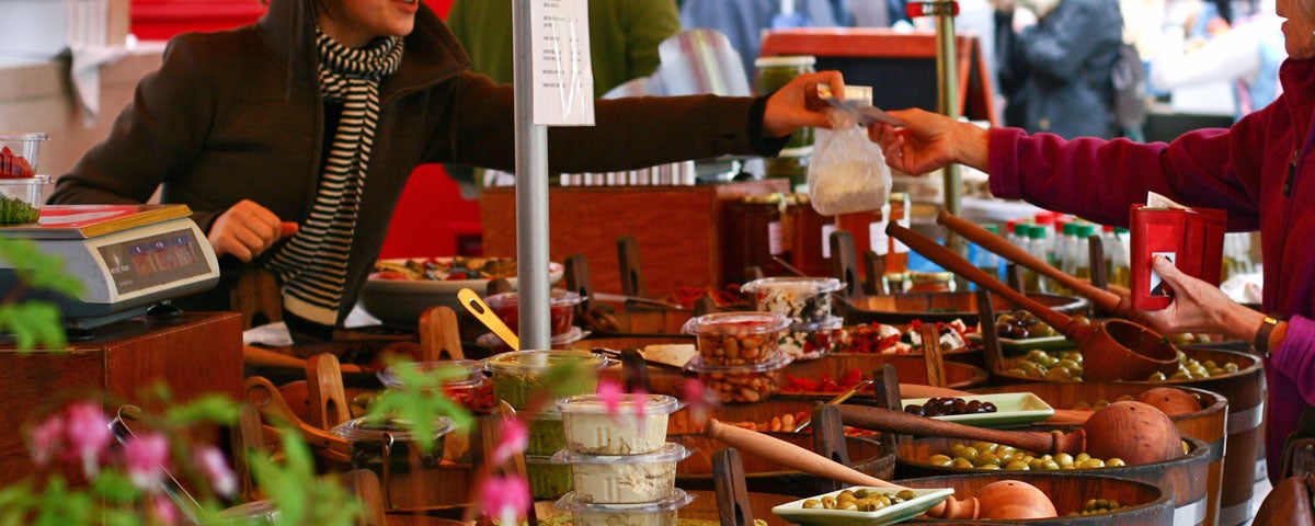 A display of olives in tubs with ladles and other fresh food at the Temple Bar Food Market