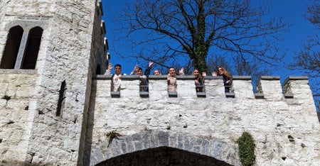 A tour group looking down over a castle wall to the camera below