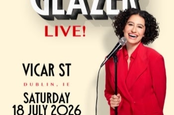 A laughing woman in red jacket holding a mic on a stand