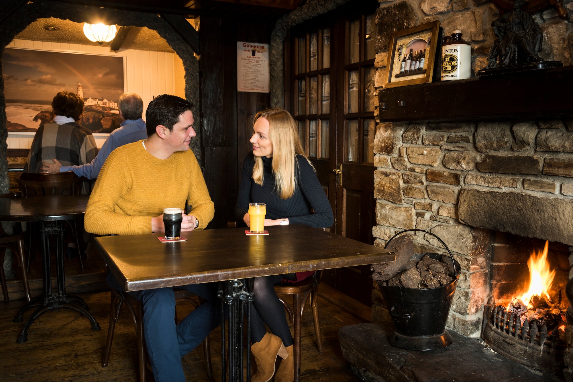 A couple having a drink in front of the fire in the Singing Pub in County Donegal