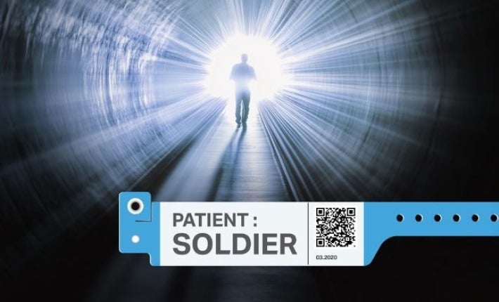 A dark tunnel with a silhouette of a figure walking down it towards a bright light